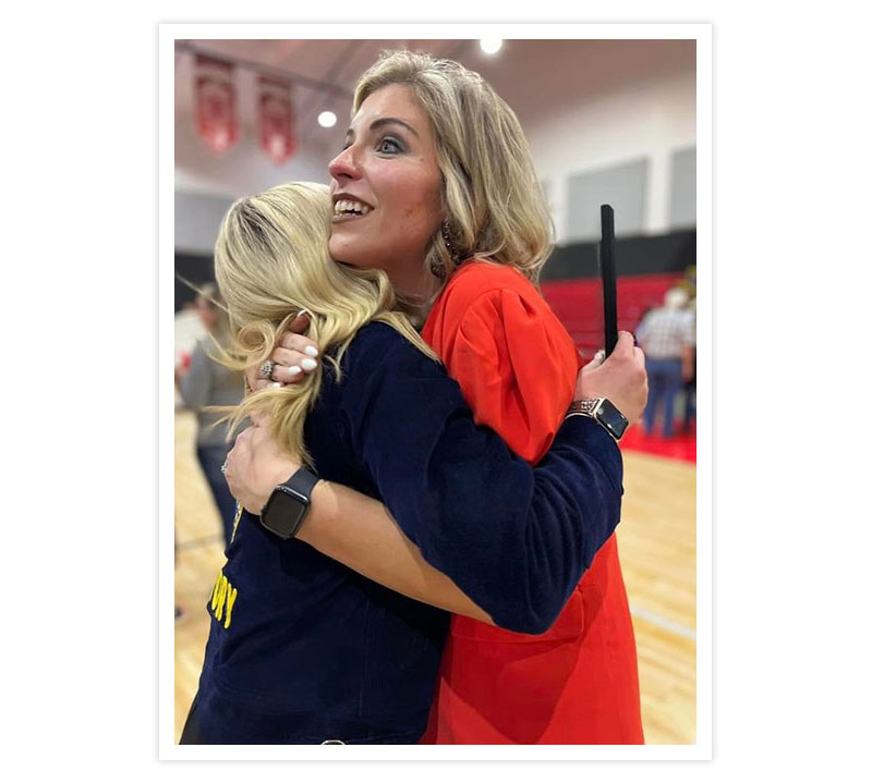 A woman with blonde hair smiling and hugging an FFA member with Blonde hair.